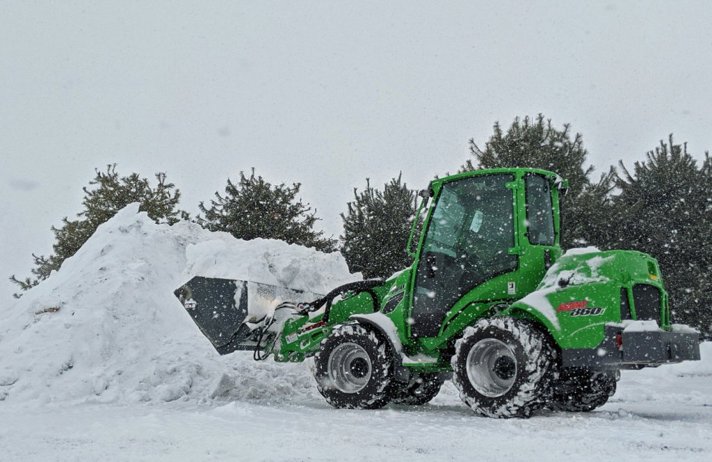 an excavator pilling up snow